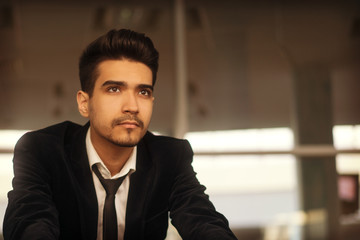 Handsome young man in a black suit, white shirt and tie training in the gym