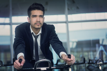 Handsome young man in a black suit, white shirt and tie training in the gym