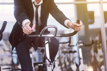 Handsome young man in a black suit, white shirt and tie training in the gym