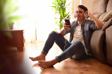 Teen listening music with headphones sitting on the floor