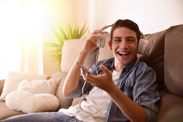 Teenager laughing with headphones sitting on couch looking straight ahead