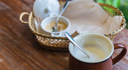 A cup of hot milk on wooden table with sugar pot
