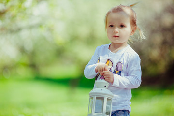 Child stands with a lantern in the garden