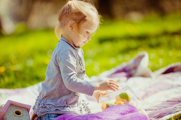 Thoughtuful little girl lies on violet plaid on the lawn