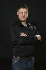 Young confident man portrait of a businessman showing by hands on a black background. Ideal for banners, registration forms, presentation, landings, presenting concept.