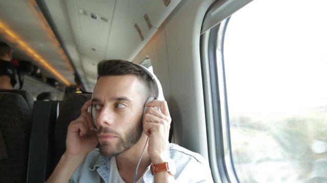 Ragazzo sente la musica con le cuffie bianche seduto su un treno 