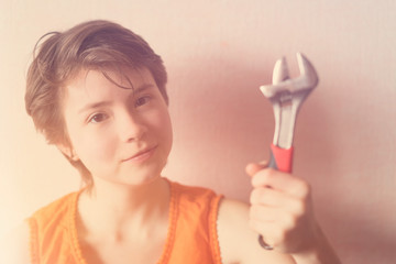 Girl teenager in an orange blouse holding wrench in the hands. Toned