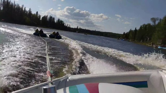 Exhilarating High Speed Water Sports. Clip Shot From The Speed Boat Of 4 People Tubing Behind It On 2 Separate Tubes.