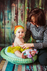 Mother plays with little child in a stripped orange hat