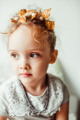 Thoughtful little girl sits before a bright window