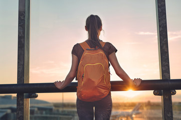 Girl at the airport window looking outside