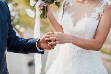 Obraz na płótnie Canvas Groom holds bride's hand with a wedding ring