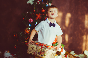 Child stands with a present box before a Christmas tree © pyrozenko13