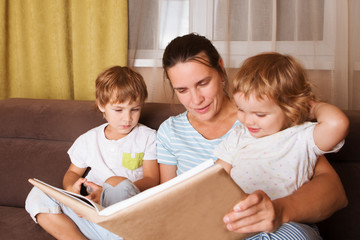 mother reads the book to two of her children the book. The happy family spends time together at home.