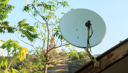 Satellite dish on roof of house with blue sky