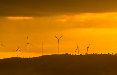 Wind turbines for electricity on a mountain at sunset.