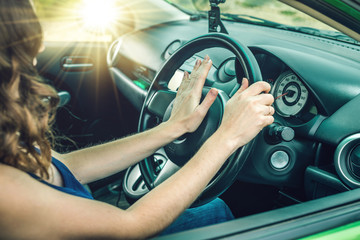 Closeup of female hand on the steering wheel presses the horn button in the car. Concept irritation...