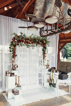 Wedding Altar Made Of White Shelves And Dark Red Flowers