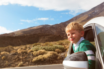 happy little boy travel by car in nature