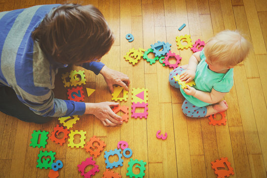 teacher and little baby playing with number puzzle