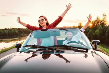 Foto op Canvas Traveling by car - happy couple in love go by cabriolet car in sunset time © Soloviova Liudmyla