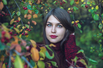 Portrait of woman in red dress in dark autumn cherry grove. Concept for fashion art design as a background for text