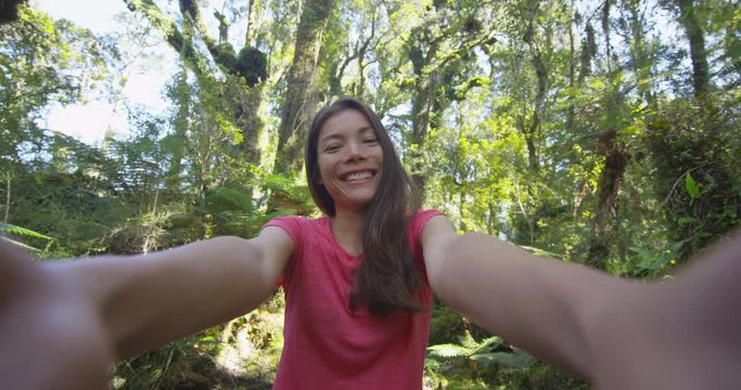Woman taking selfie video hiking in New Zealand kissing and waving hello to camera in swamp forest nature landscape in Ship Creek, West Coast of New Zealand. Happy tourist girl sightseeing New Zealand