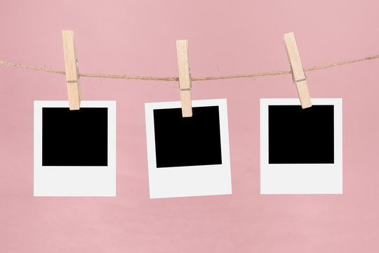 Clothesline with three empty picture frames and clothespins on a pink background