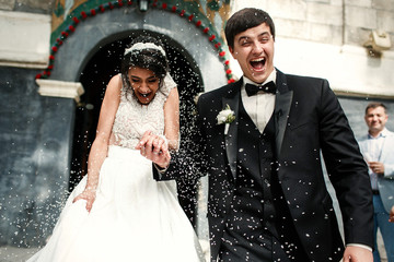 Friends throw rice on newlyweds while they walk out of the church
