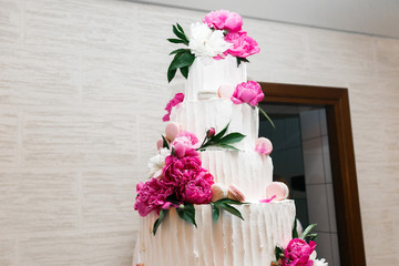 Layered wedding cake decorated with pink peonies