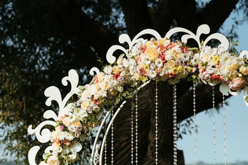 details of beautiful wedding arch of flowers on a background green field with trees