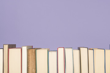 Row of books on a lavender purple background with space for copy