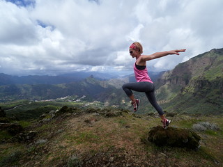 young happy woman jumping on top of the mountain