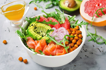 Healthy salad bowl with salmon, grapefruit, spicy chickpeas, avocado, red onion and arugula