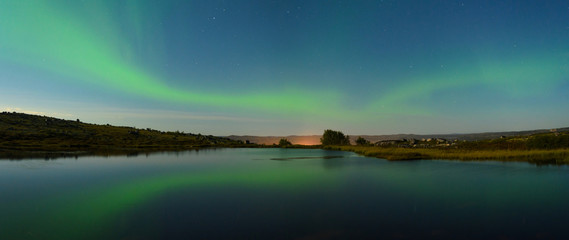 Autumn Aurora over the hills and reflected in the lake.