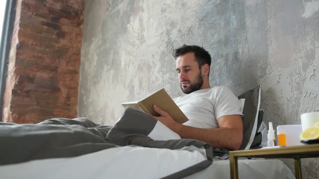 Ill man reading book and feeling sharp twinge of pain