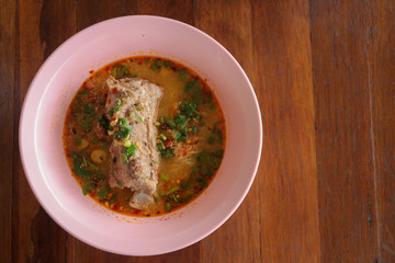 Spicy noodle pork bone soup on wood background.