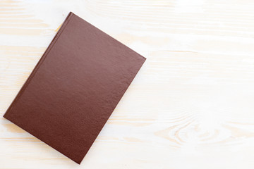 Close-up of brown notebook on light wooden background
