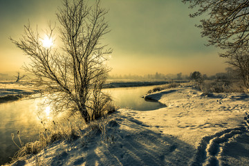 Winter river landscape, moody scenery with morning sun reflection in the water
