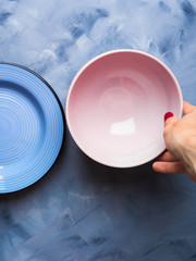 Pastel color plate and bowl with woman's hand holding it