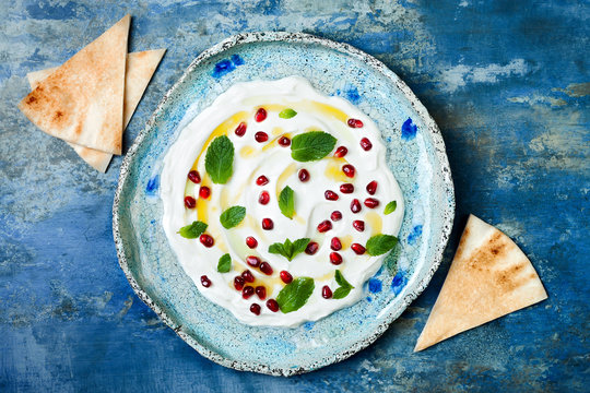 Labneh middle eastern lebanese cream cheese dip with pomegranate, mint and pita. Top view, overhead