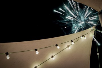 Fairy lights on a marquee with a firework exploding in the background