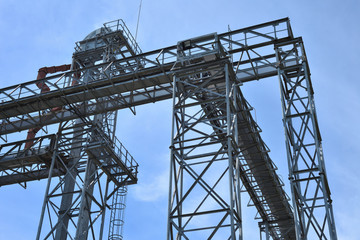 Fototapeta na wymiar Fragment of metal grain elevator in facility with silos.