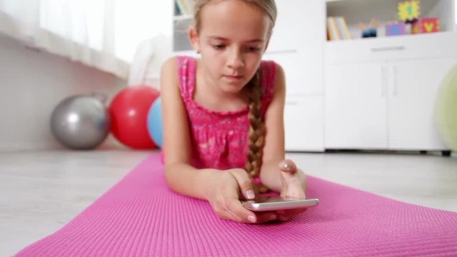 Young girl hands using smartphone lying on the floor - camera dolly, focus on hands