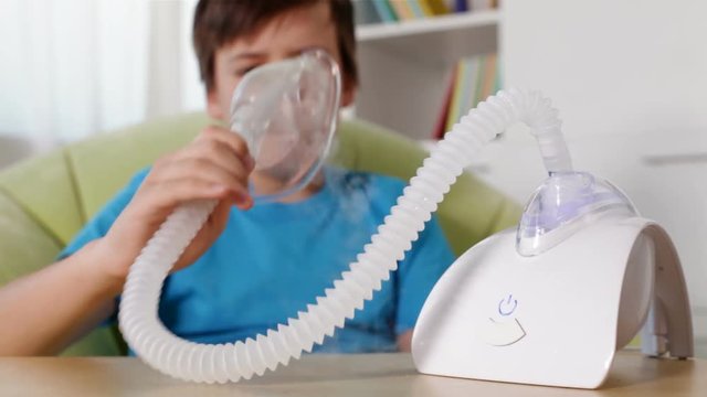 Boy using nebuliser inhaler with mask - rack focus, static camera
