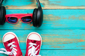 the red sneakers with pink sunglasses and headphone on old blue wooden floor background. copy space for graphic designer