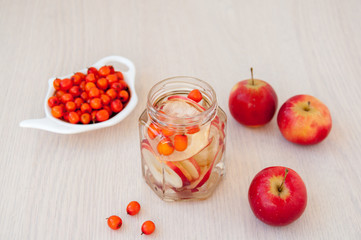 Drink from sea buckthorn and red apples on the table