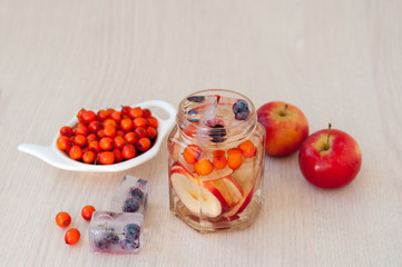 Water with sea buckthorn, forest berries and red apples