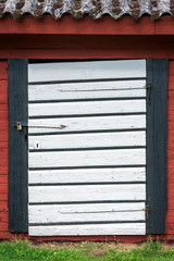 Closed white barn door on red and black barn.