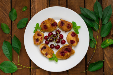 Pancakes with cherries. Wooden background. Close-up. Top view